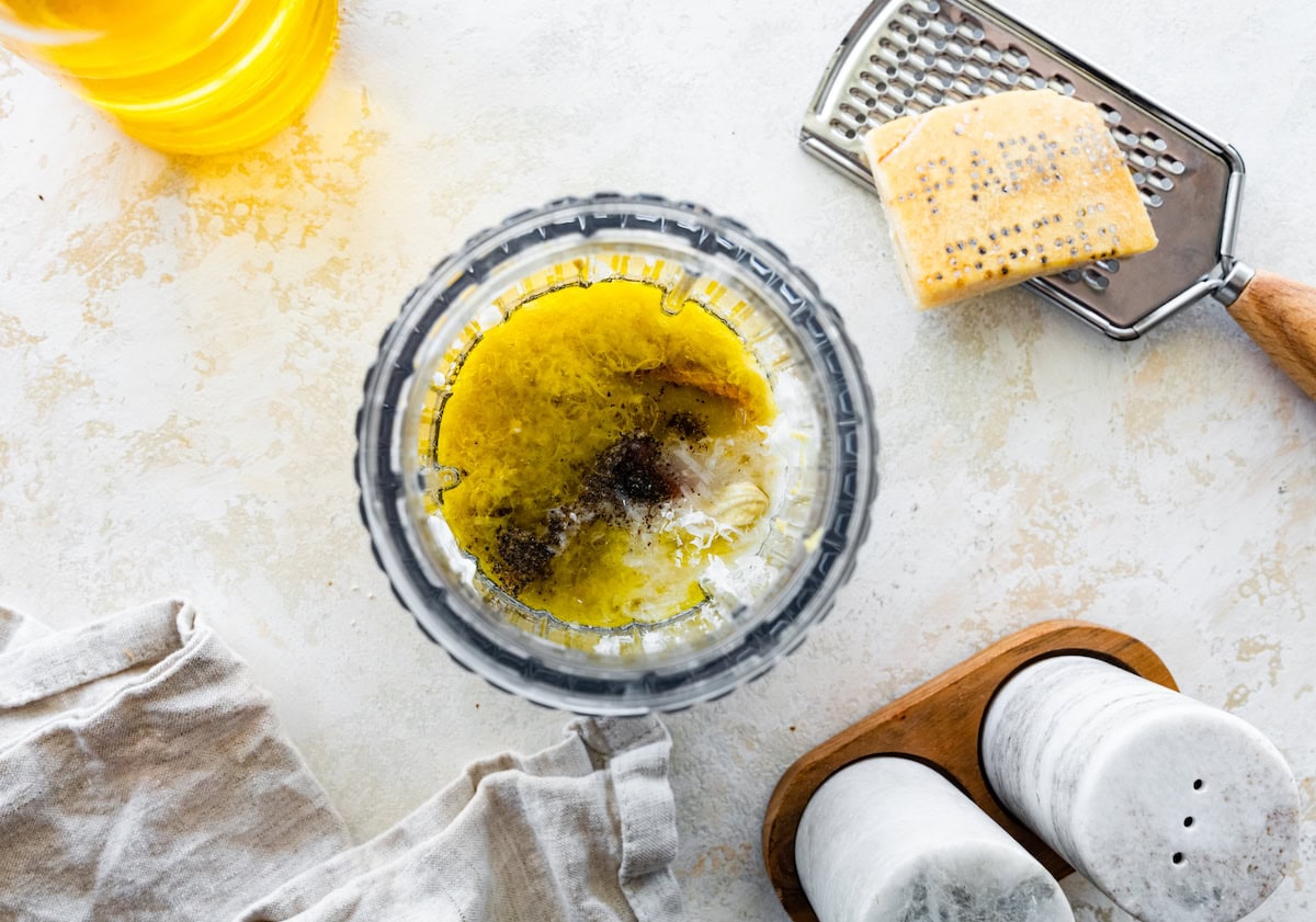A glass cup of ingredients used for a dressing for the chicken caesar pasta salad.