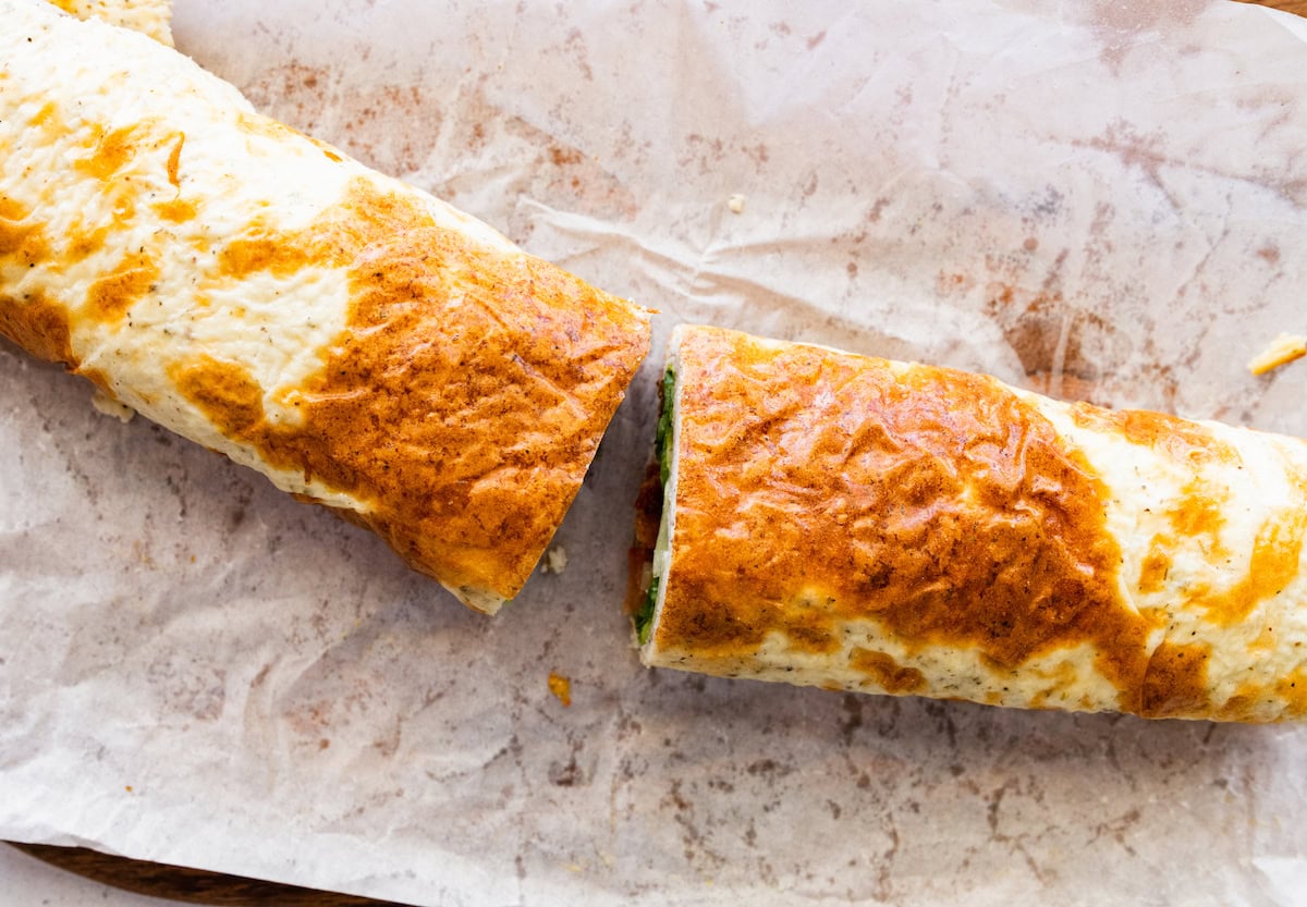 Two sections of a cottage cheese wrap cut in half on a piece of parchment paper.