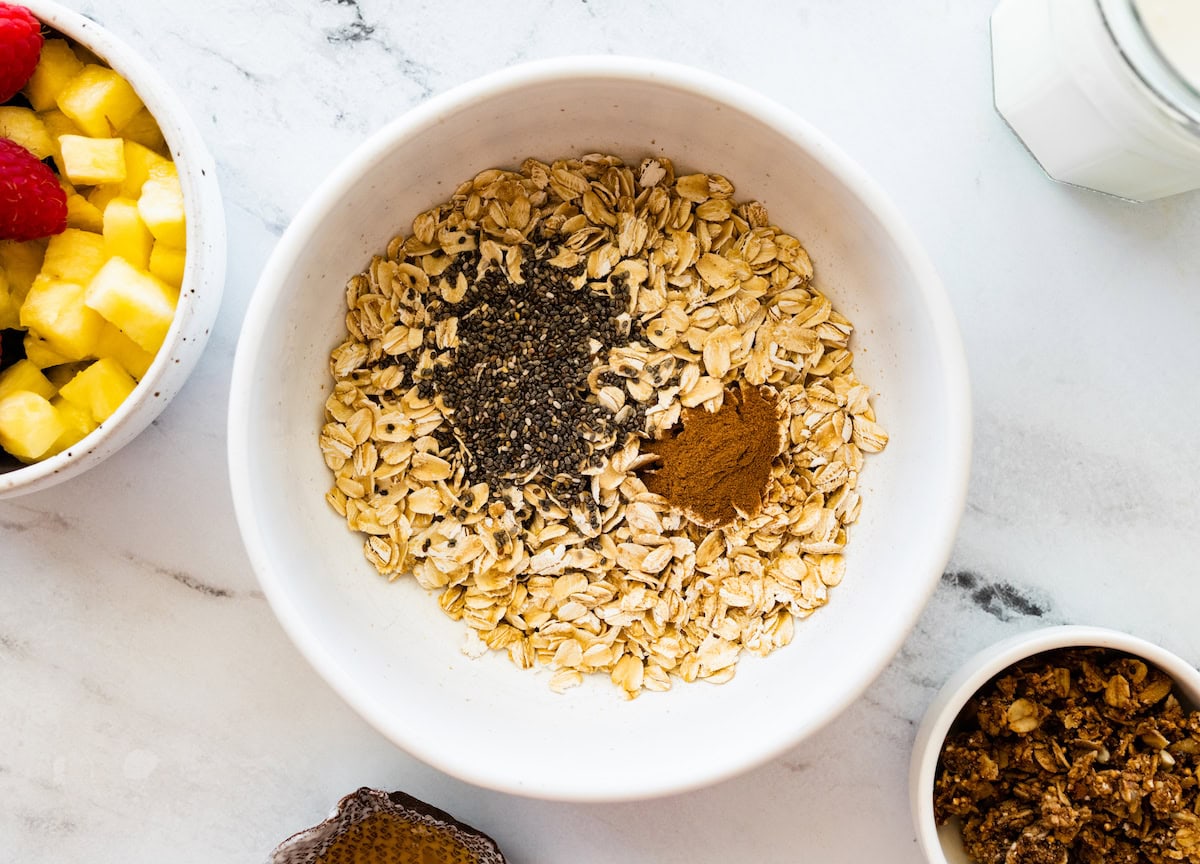 A large white bowl of rolled oats, chia seeds, and cinnamon.