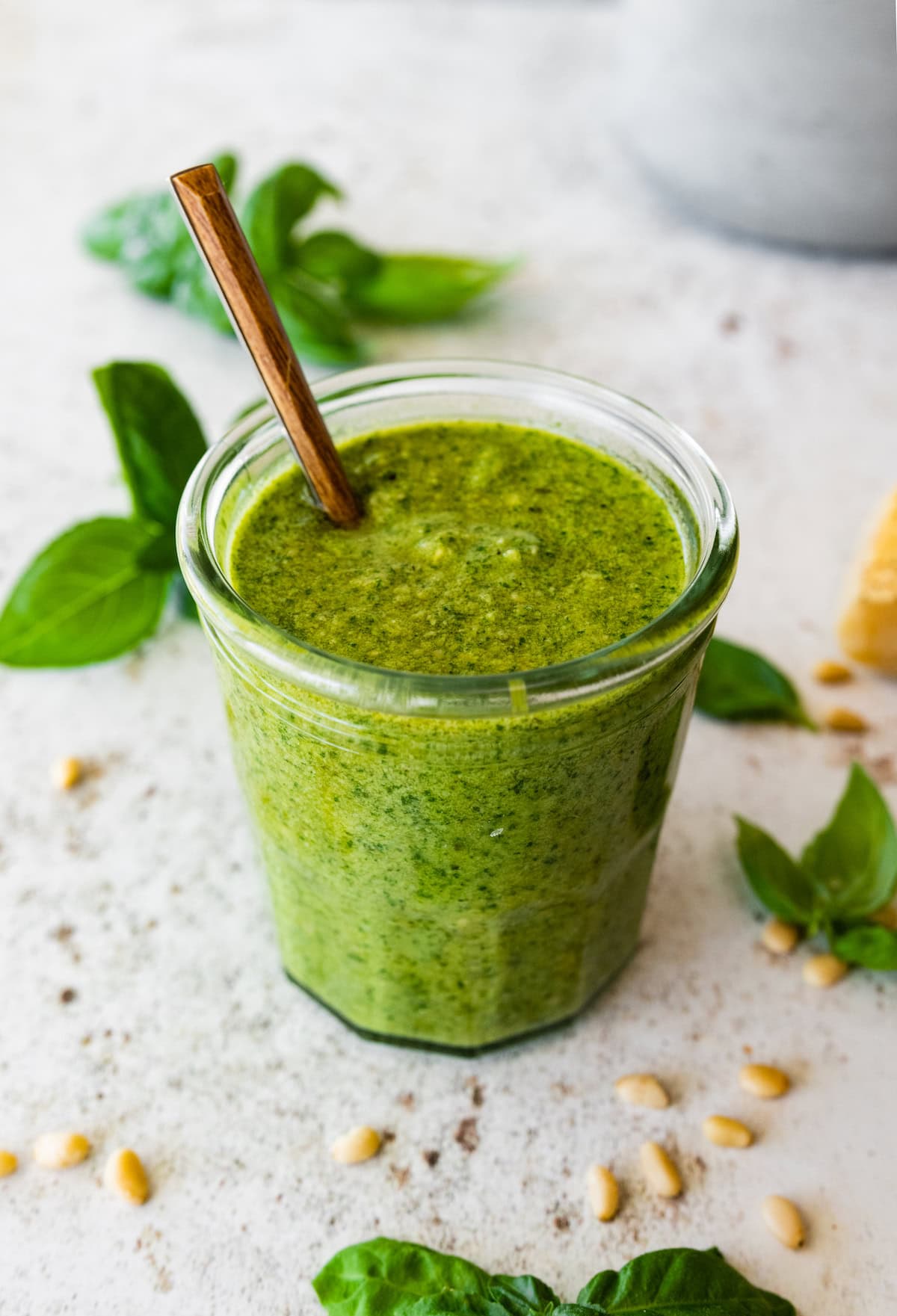 Glass jar full of homemade pesto with a spoon in the jar.