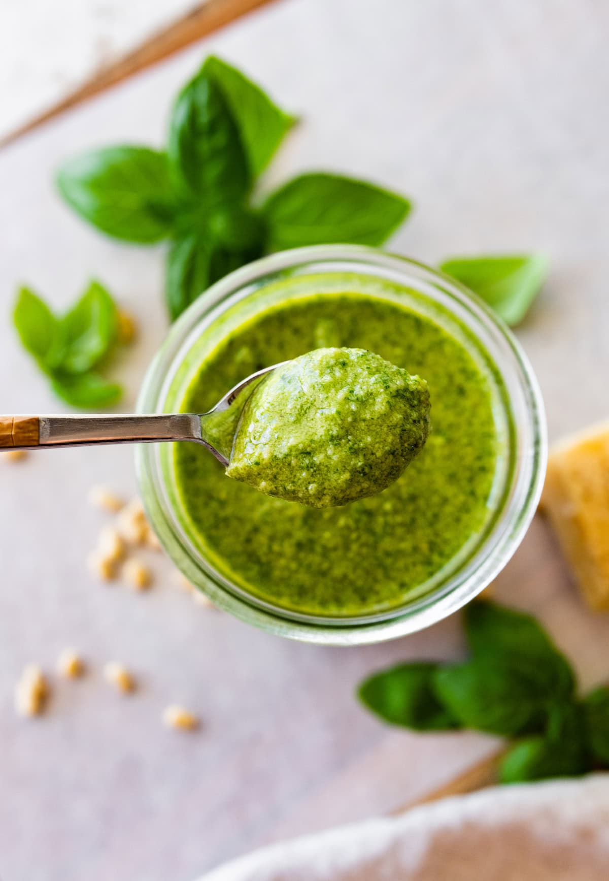 Overhead photo of a glass jar full of homemade pesto with a spoon scooping pesto out.