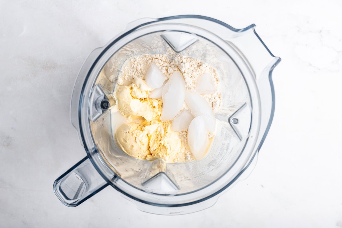 Ice cream, ice cubes, protein powder, and milk in a blender.