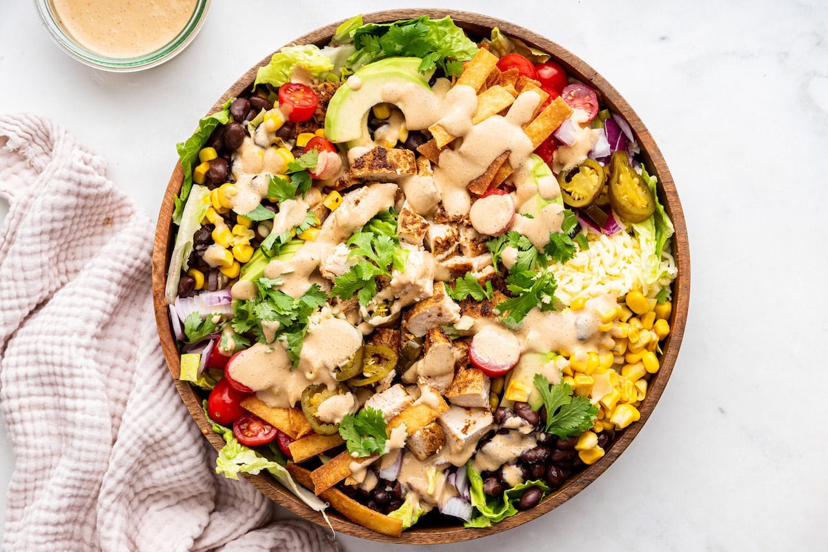 A large wooden bowl of a southwest chicken salad with a southwest dressing.