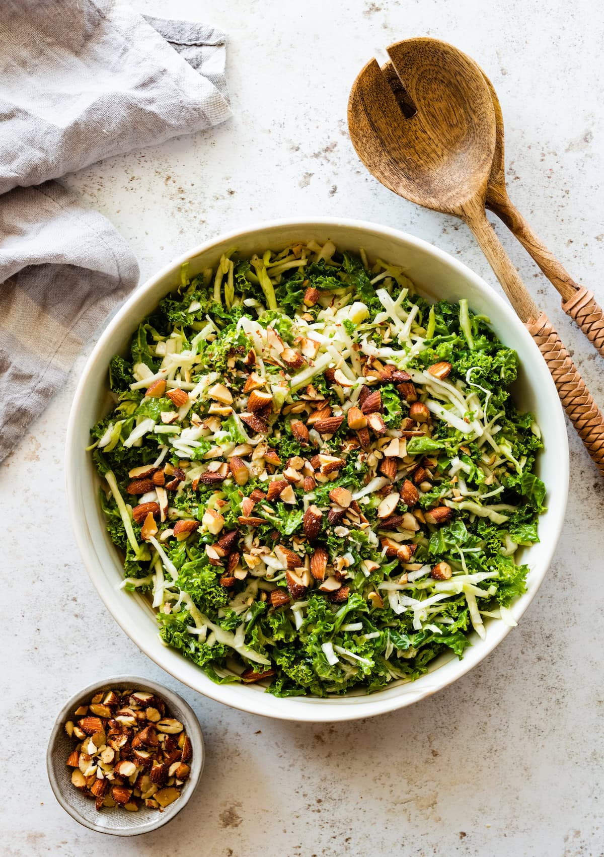 A large bowl of kale crunch salad topped with crushed almonds.
