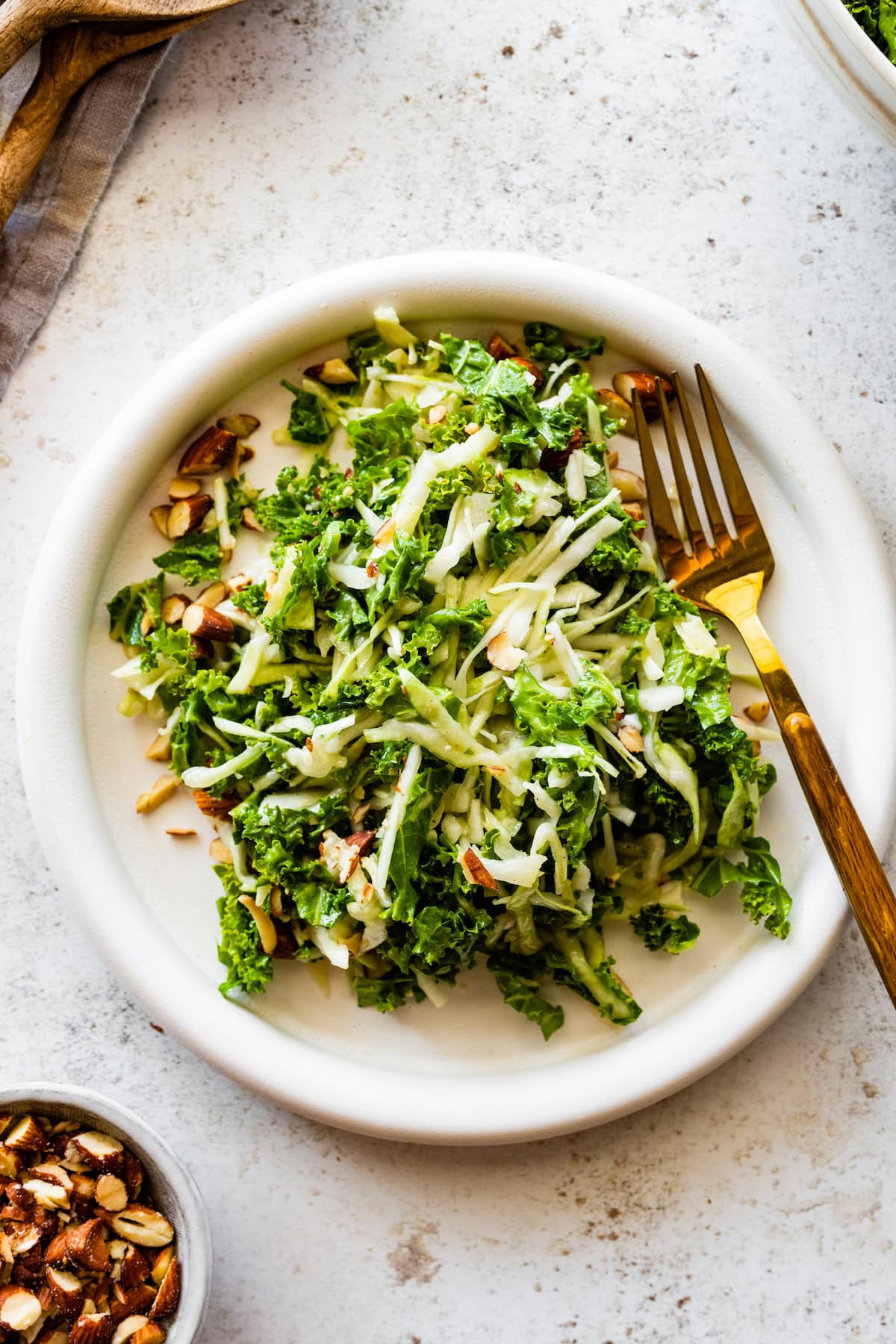 A plate of a kale crunch salad topped with crushed almonds.