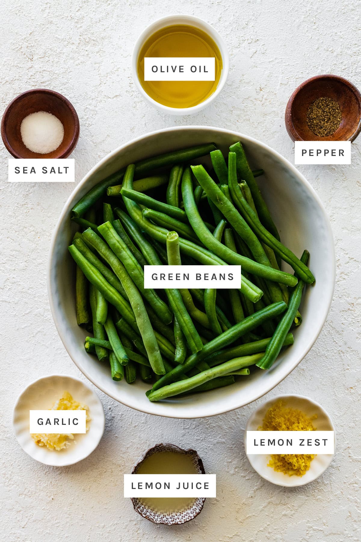 Ingredients measured out to make Sautéed Green Beans: sea salt, olive oil, pepper, green beans, garlic, lemon juice and lemon zest.