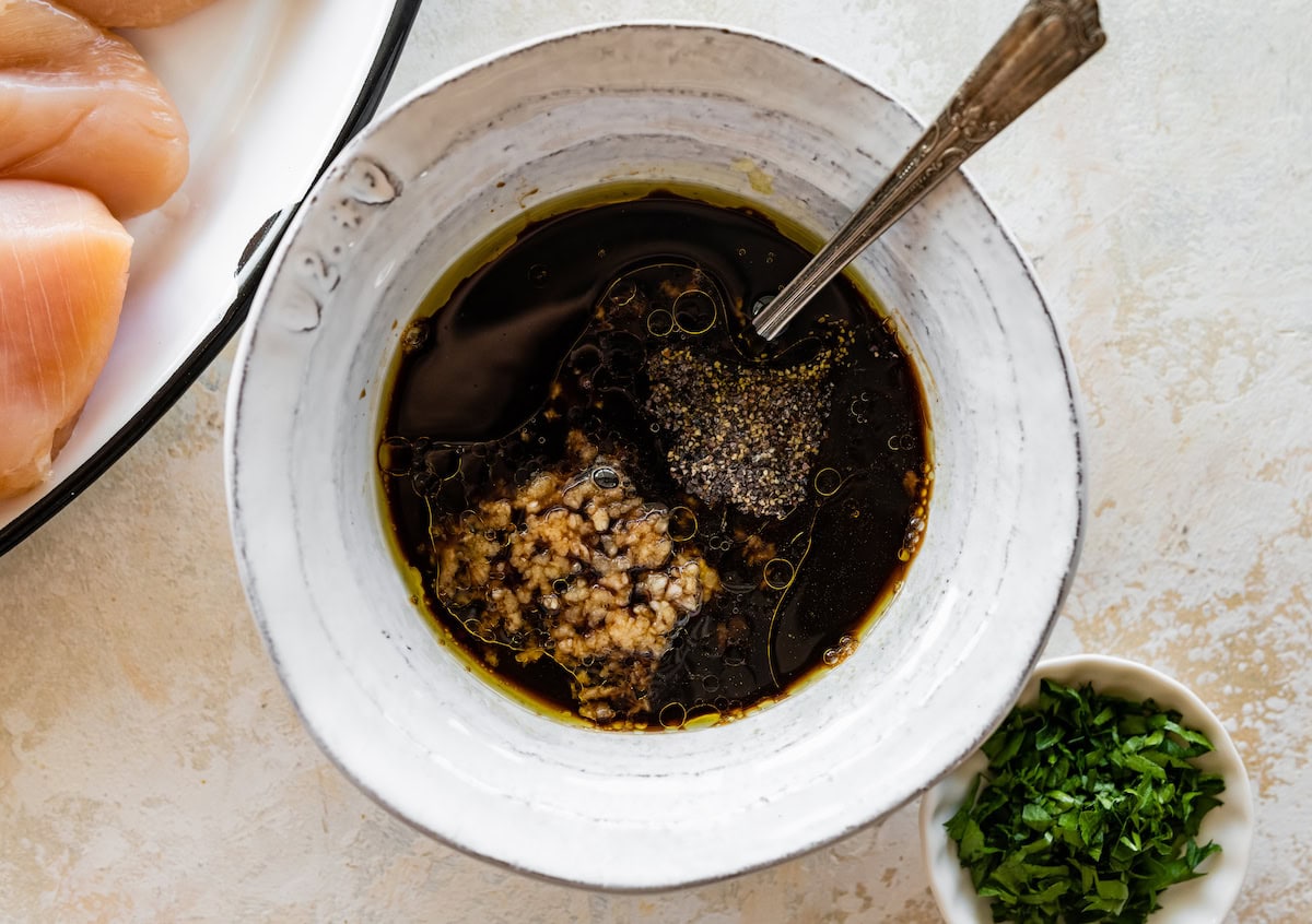 A small bowl of lemon juice, balsamic vinegar, soy sauce, brown sugar, olive oil, worcestershire sauce, garlic, salt and pepper.