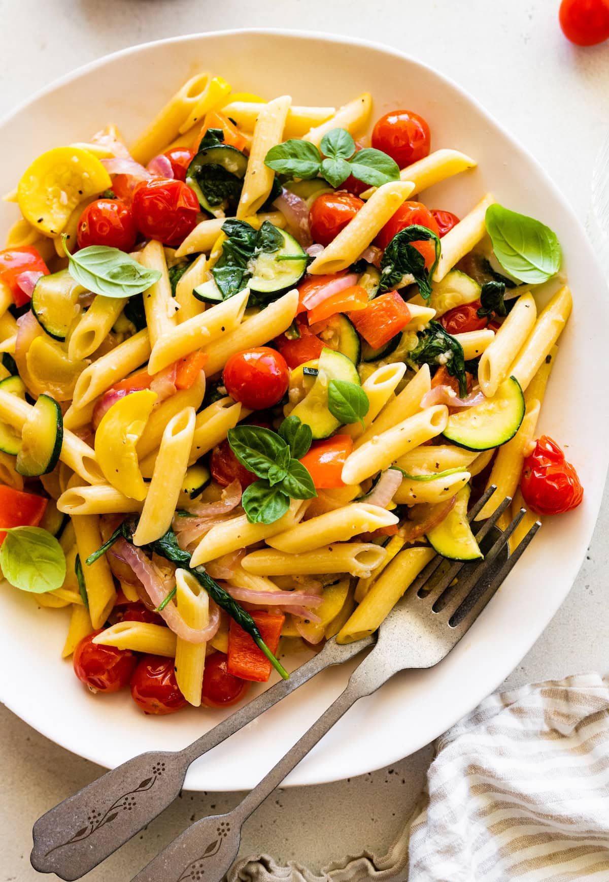 A serving of pasta primavera on a plate topped with fresh herbs.