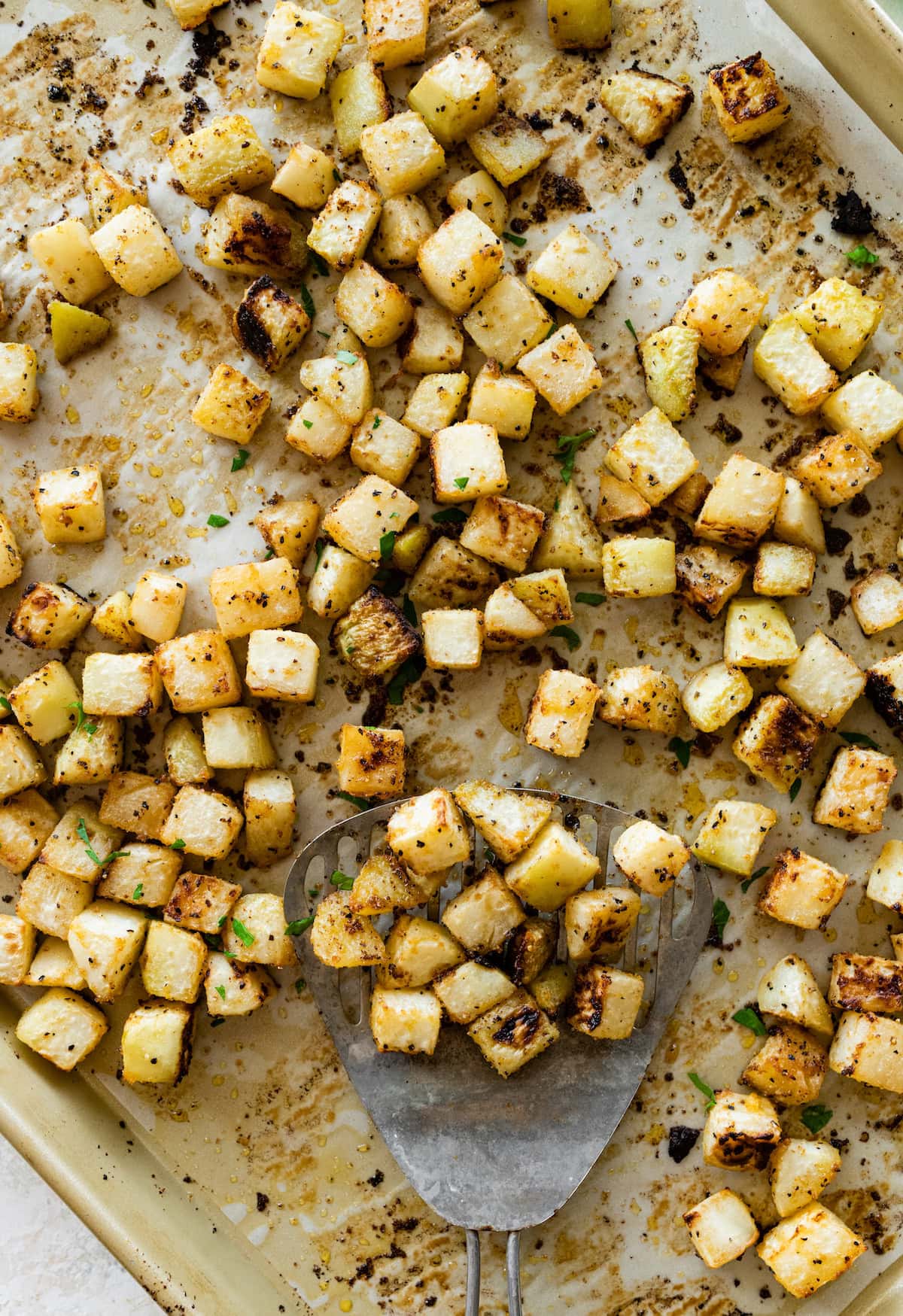 A large baking tray with cubed and roasted kohlrabi.