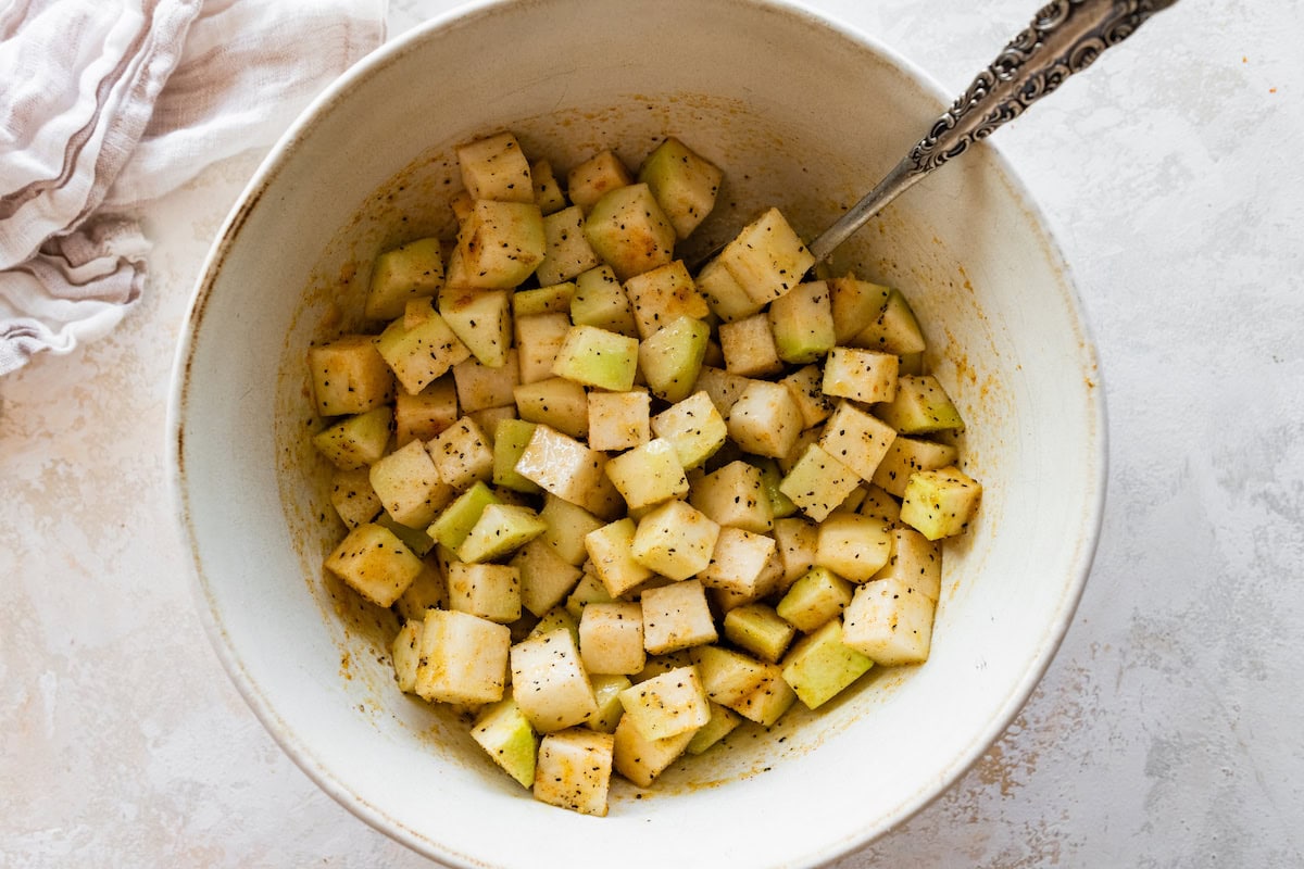 Seasoned and cubed kohlrabi in a large mixing bowl.