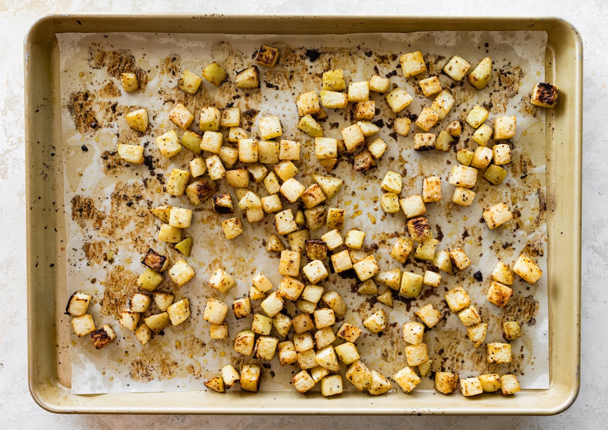 Cubed kohlrabi on a baking tray after being roasted in the oven.