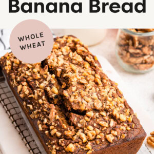 Loaf of Pumpkin Banana Bread topped with nuts on a cooling rack.
