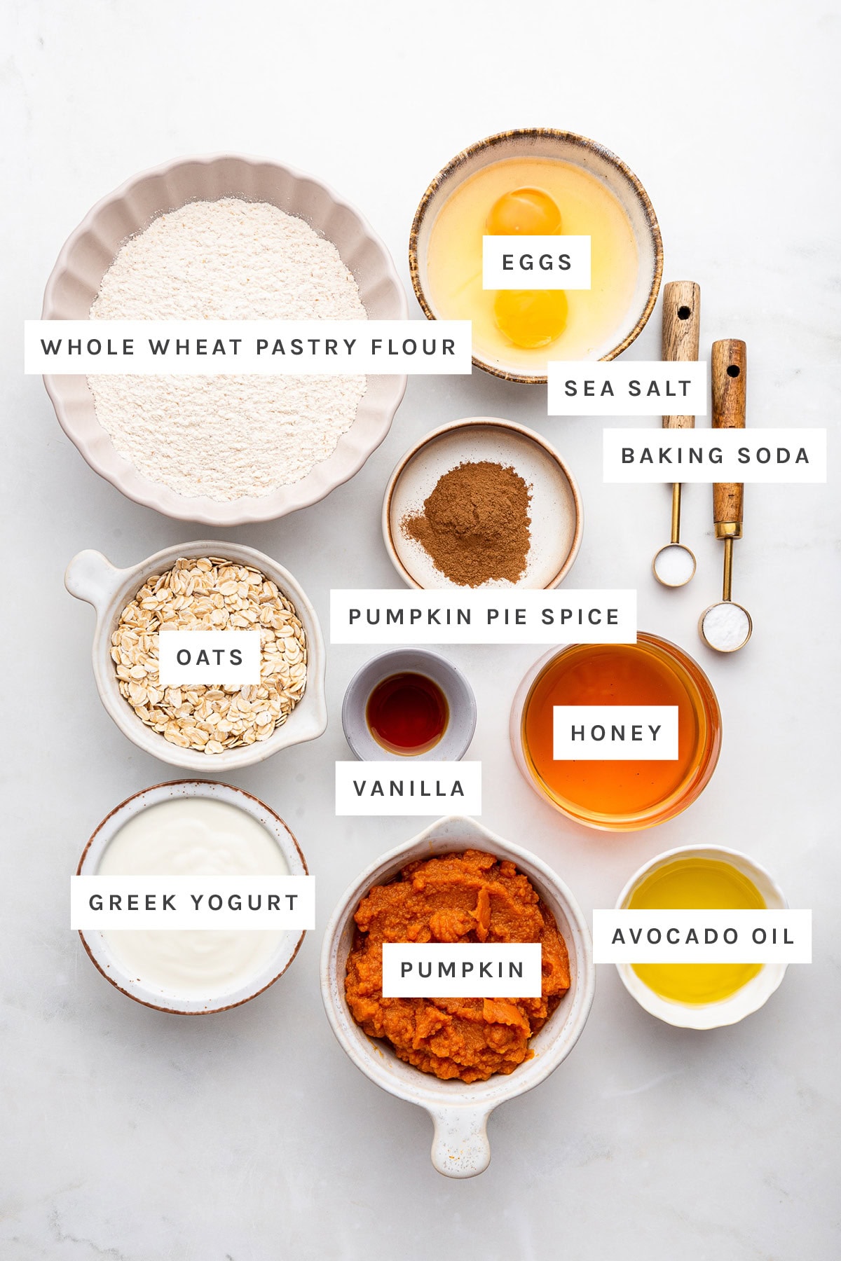 Ingredients measured out to make Healthy Pumpkin Muffins: whole wheat pastry flour, eggs, sea salt, baking soda, pumpkin pie spice, oats, vanilla, honey, Greek yogurt, pumpkin and avocado oil.