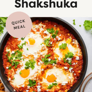 Shakshuka in a skillet-- tomato based veggie skillet topped with sunny side up eggs.