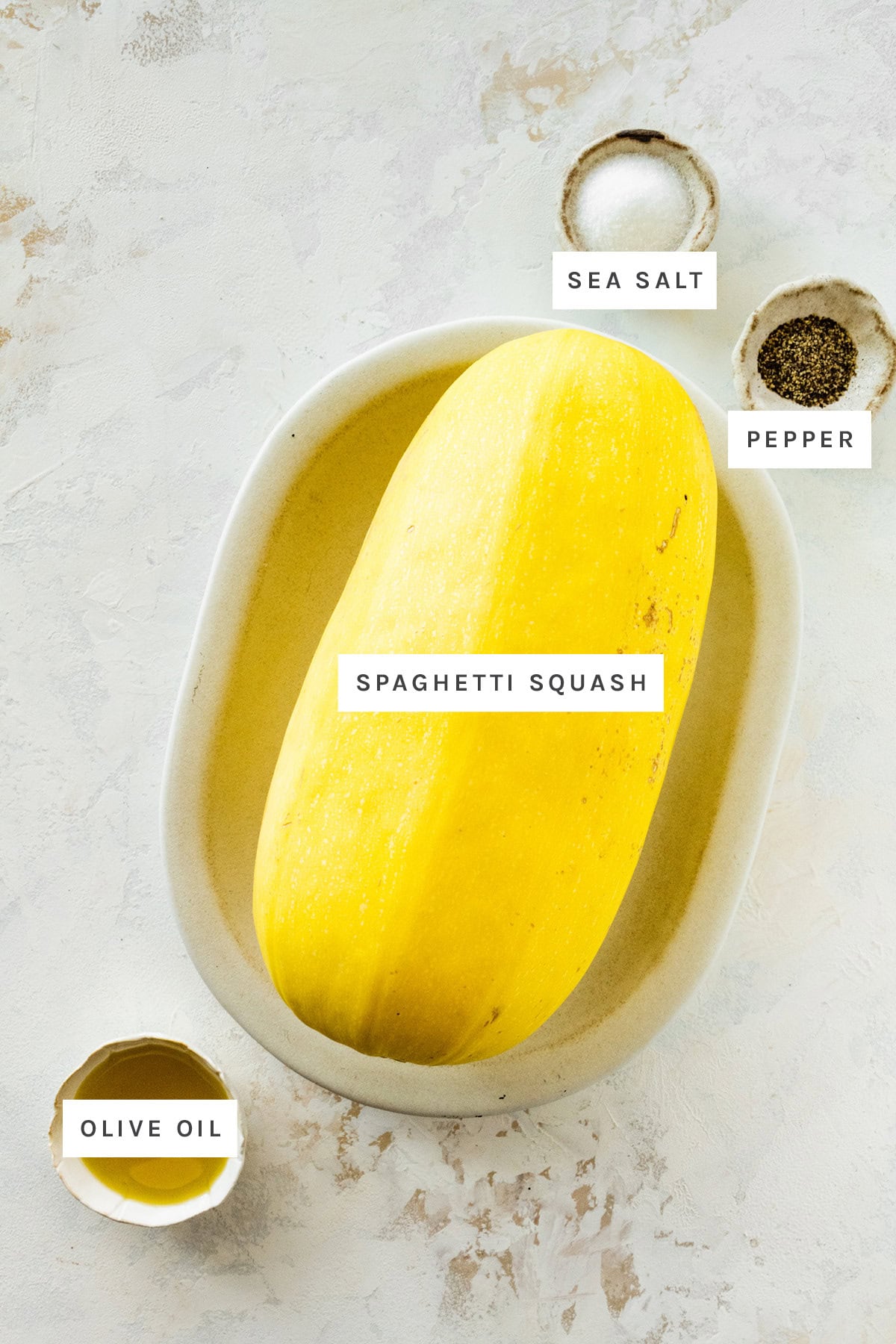 Ingredients measured out to make spaghetti squash: spaghetti squash, sea salt, pepper and olive oil.