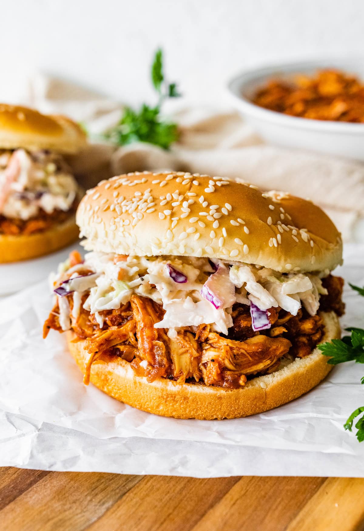 A BBQ shredded chicken sandwich on parchment paper.