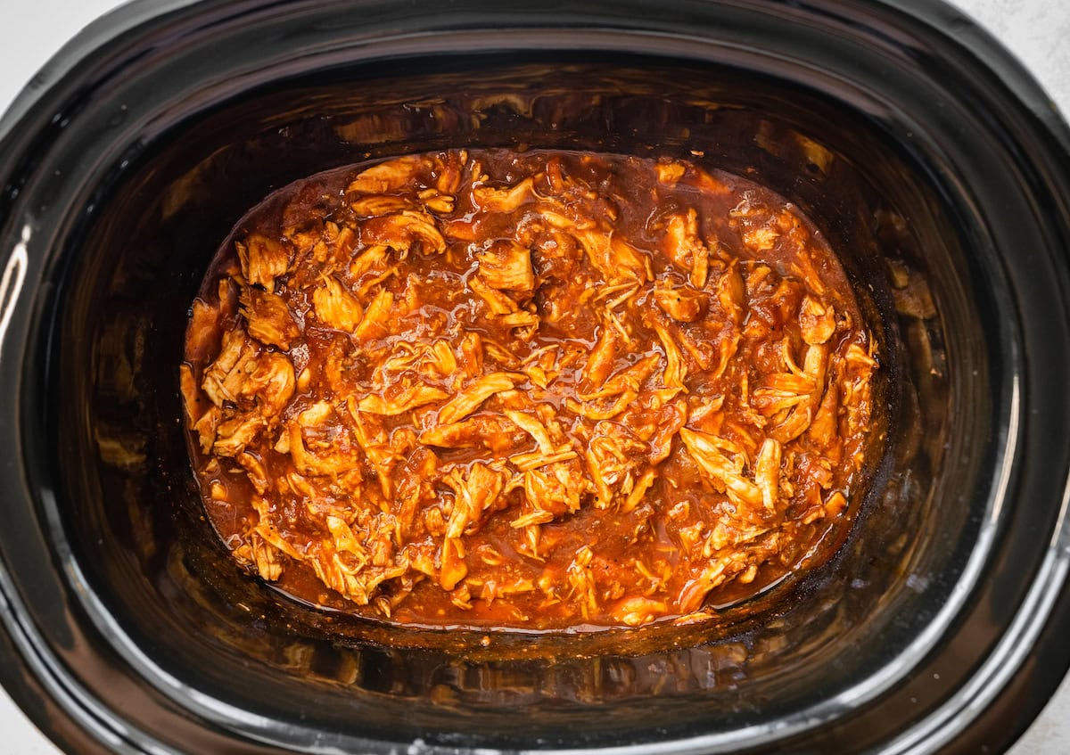 A slow cooker full of BBQ shredded chicken.
