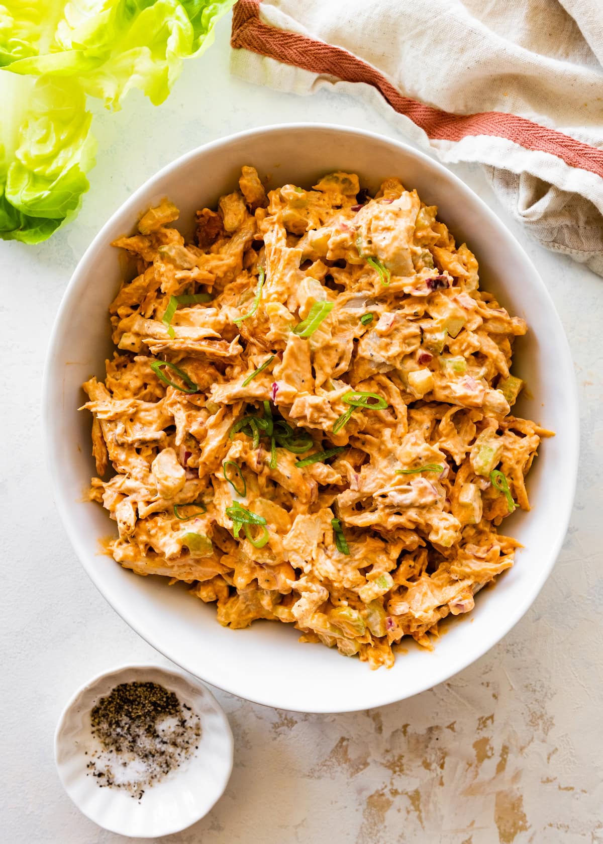 A bowl of buffalo chicken salad garnished with green onion.