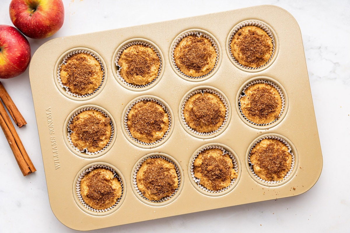 Apple muffins placed in a muffin tin before being baked.
