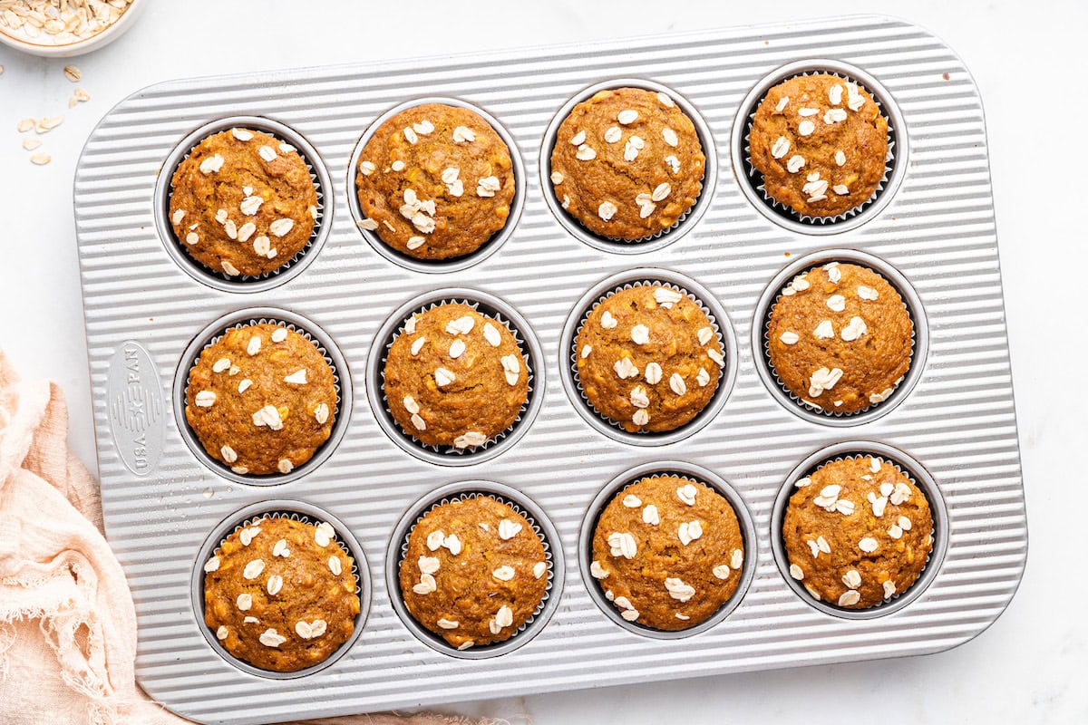 Twelve pumpkin muffins in a muffin tin after being baked.