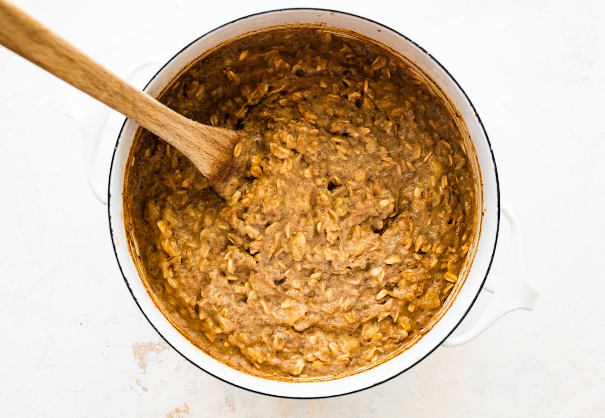 Cooked peanut butter oatmeal in a pot with a wooden spoon.