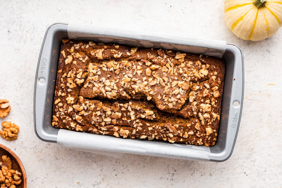 A loaf of pumpkin banana bread in a bread pan after being baked.