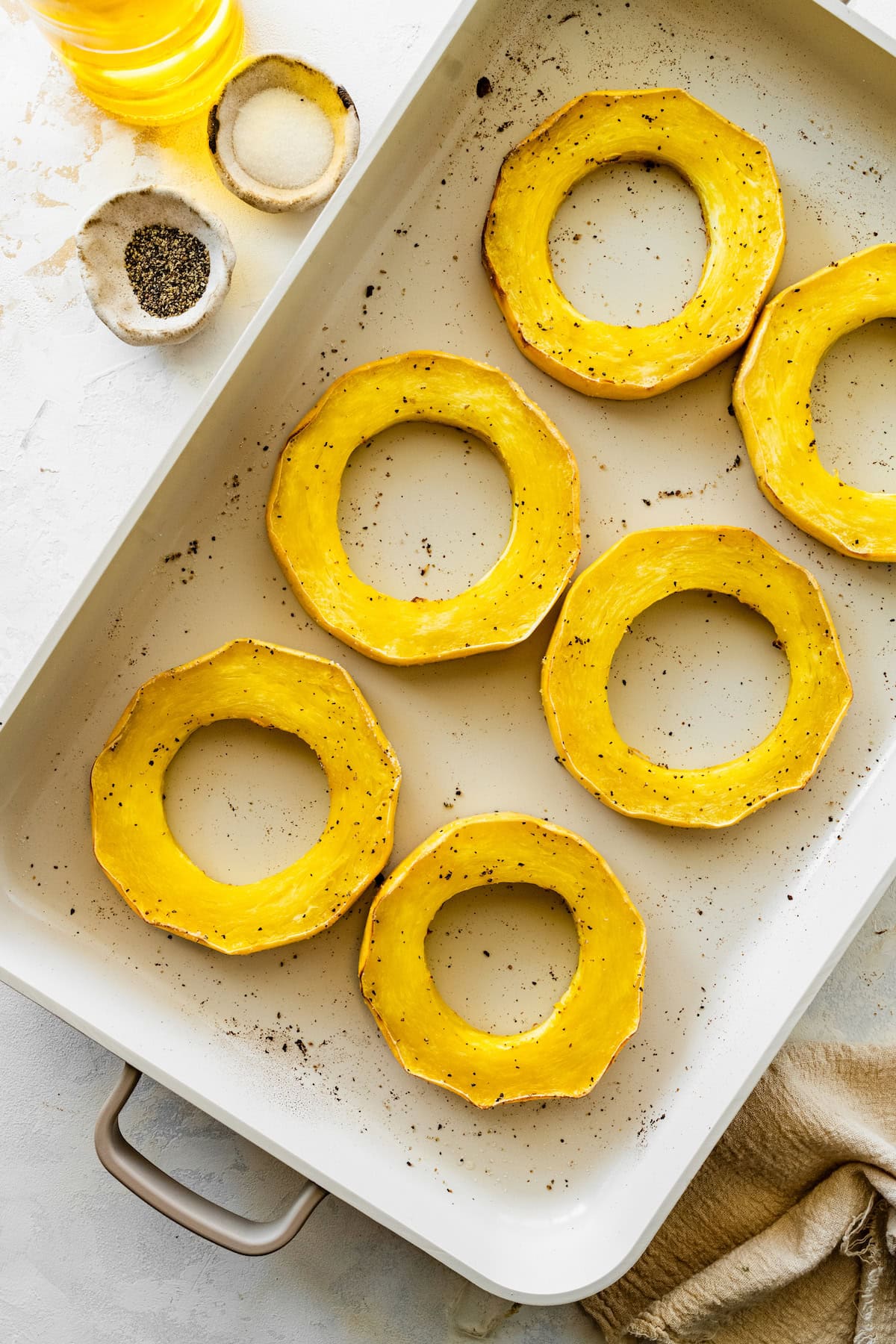 Six round spaghetti squash rings roasted in a baking dish.