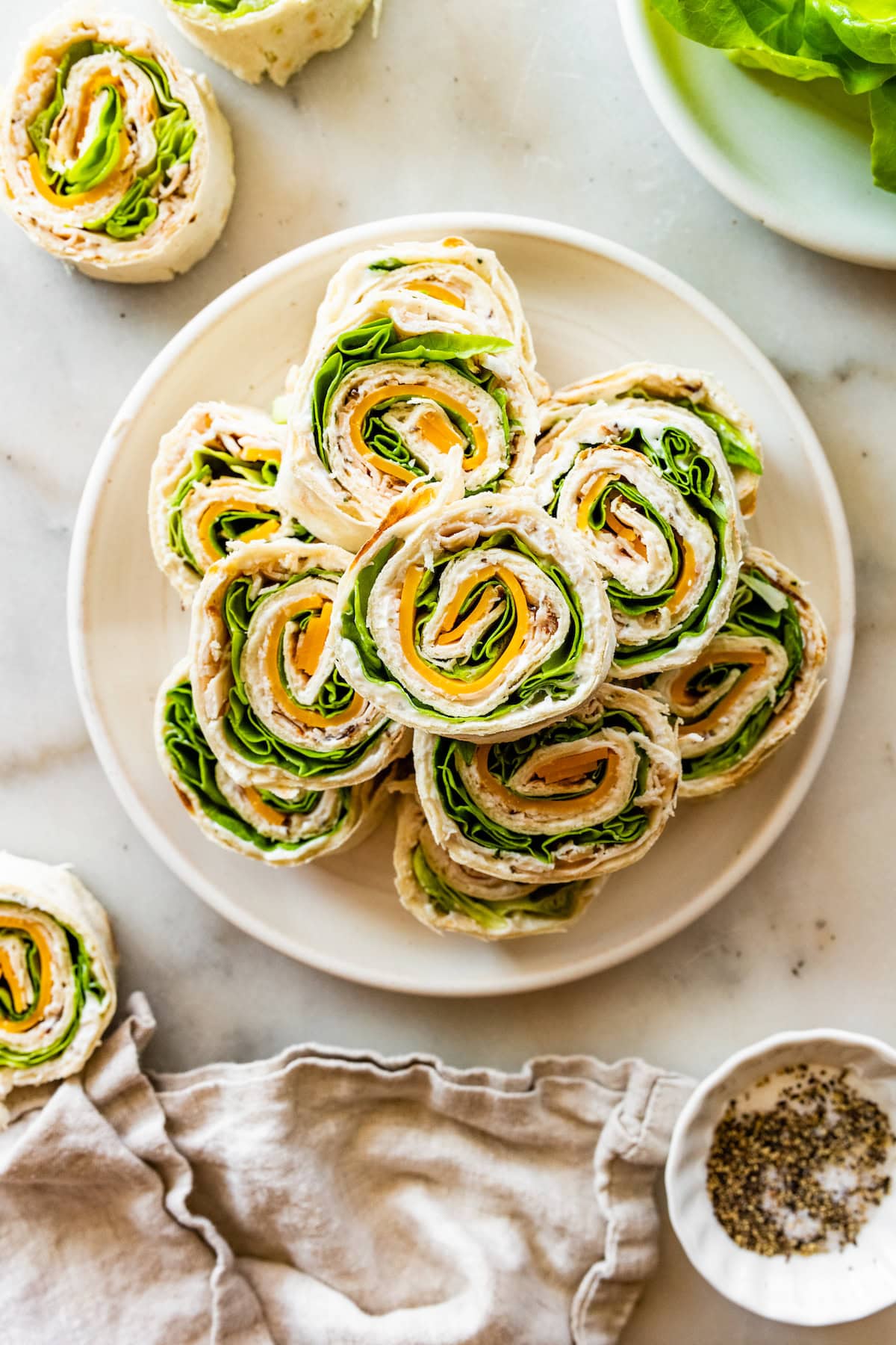 Multiple turkey pinwheel sandwiches stacked on a plate.