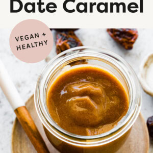 Small glass jar of date caramel with a spoon and dates next to the jar.