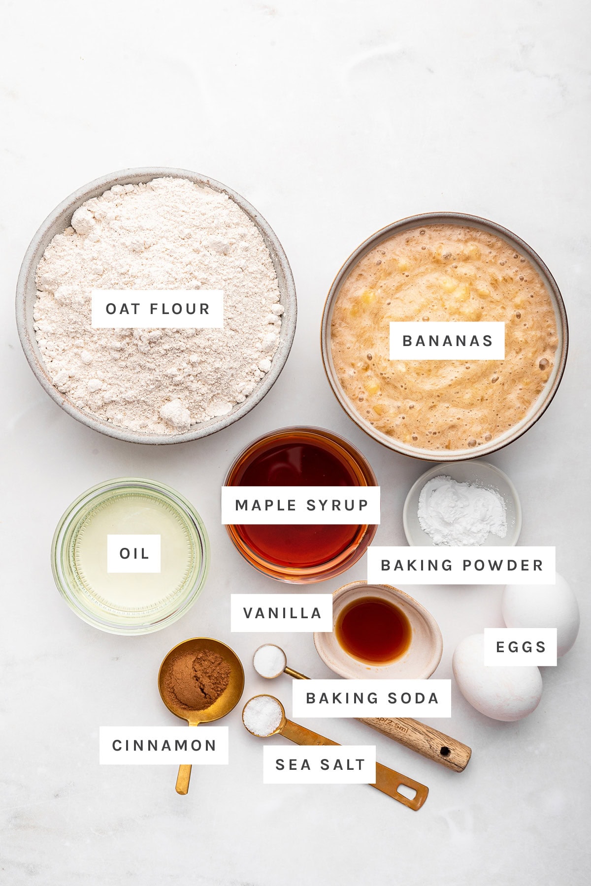 Ingredients measured out to make Oat Flour Banana Bread: oat flour, bananas, maple syrup, oil, baking powder, vanilla, eggs, baking soda, sea salt and cinnamon.