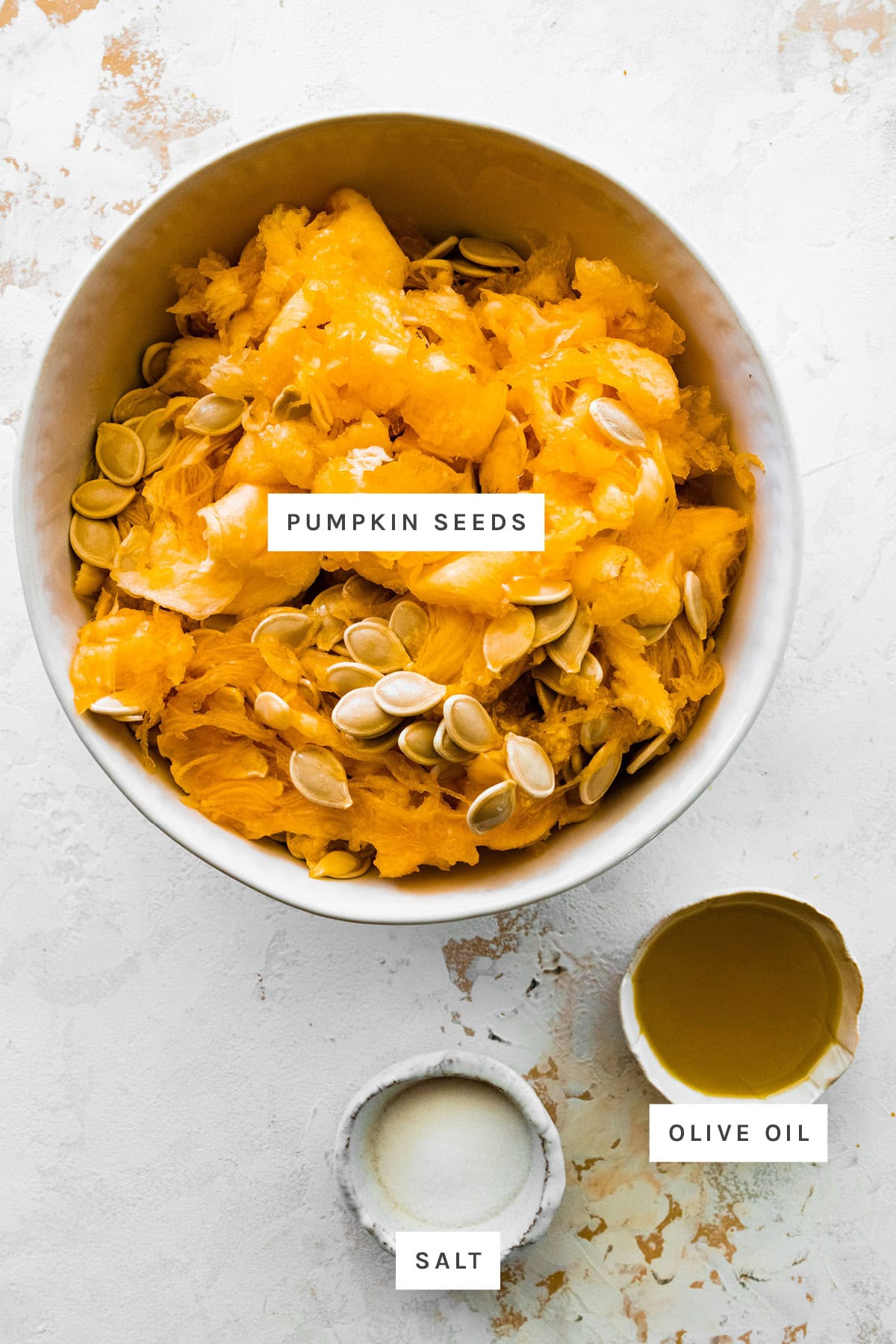 Ingredients measured out to make Roasted Pumpkin Seeds: pumpkin seeds, salt and olive oil.