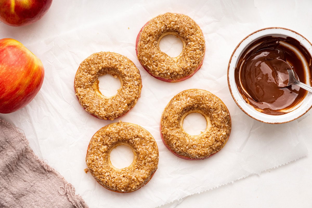 Circular apple slices with almond butter, coconut, and maple syrup on top.