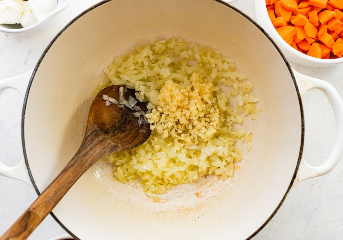 A large pot of translucent onion with chopped garlic and ginger added to it.