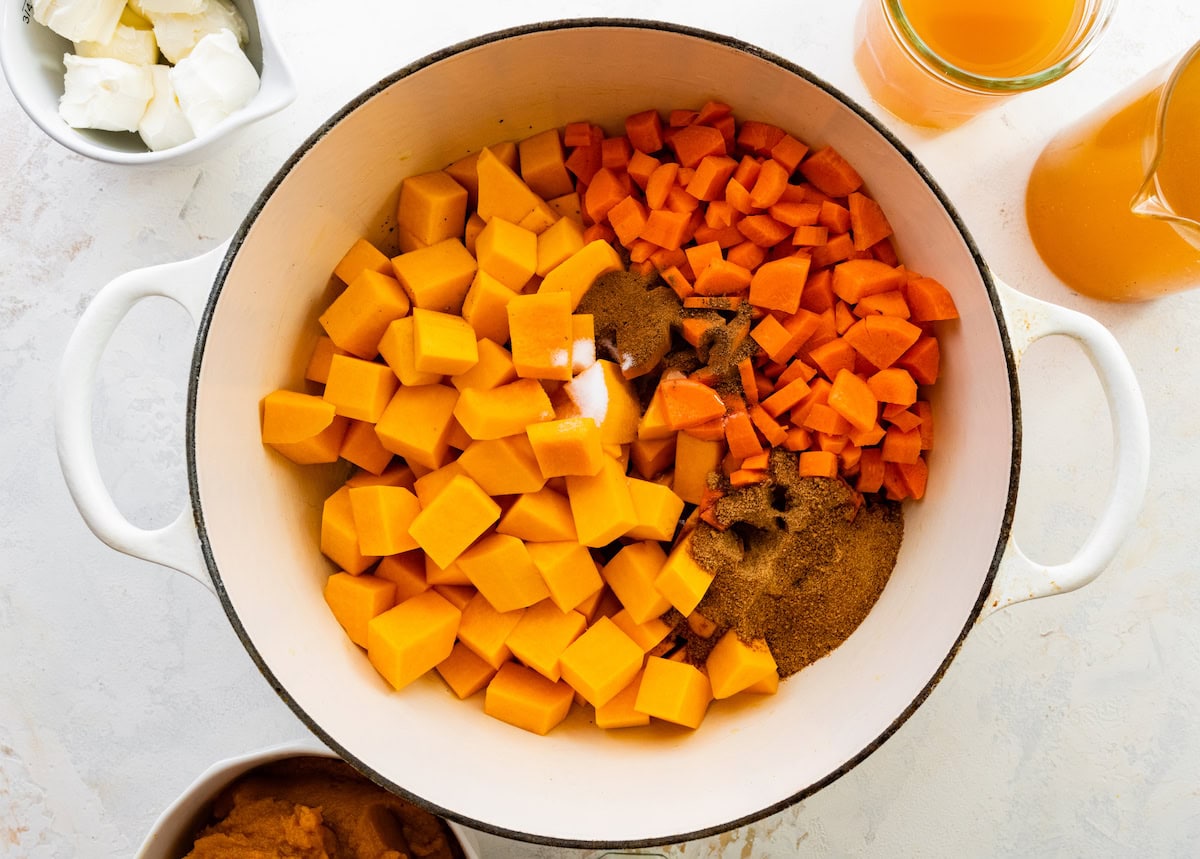 Diced butternut squash, chopped carrots, cinnamon, nutmeg, and brown sugar added to a large pot.