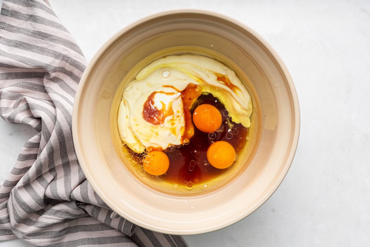 A large bowl of eggs, yogurt, oil, and maples syrup used for a french yogurt cake.
