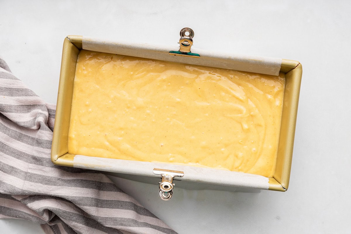 French yogurt cake batter is added to a prepared loaf pan.