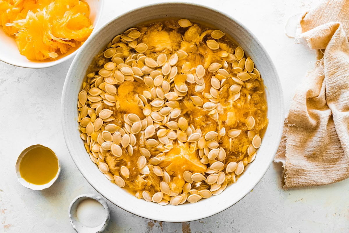 A large bowl of pumpkin seeds in pumpkin pulp and water.