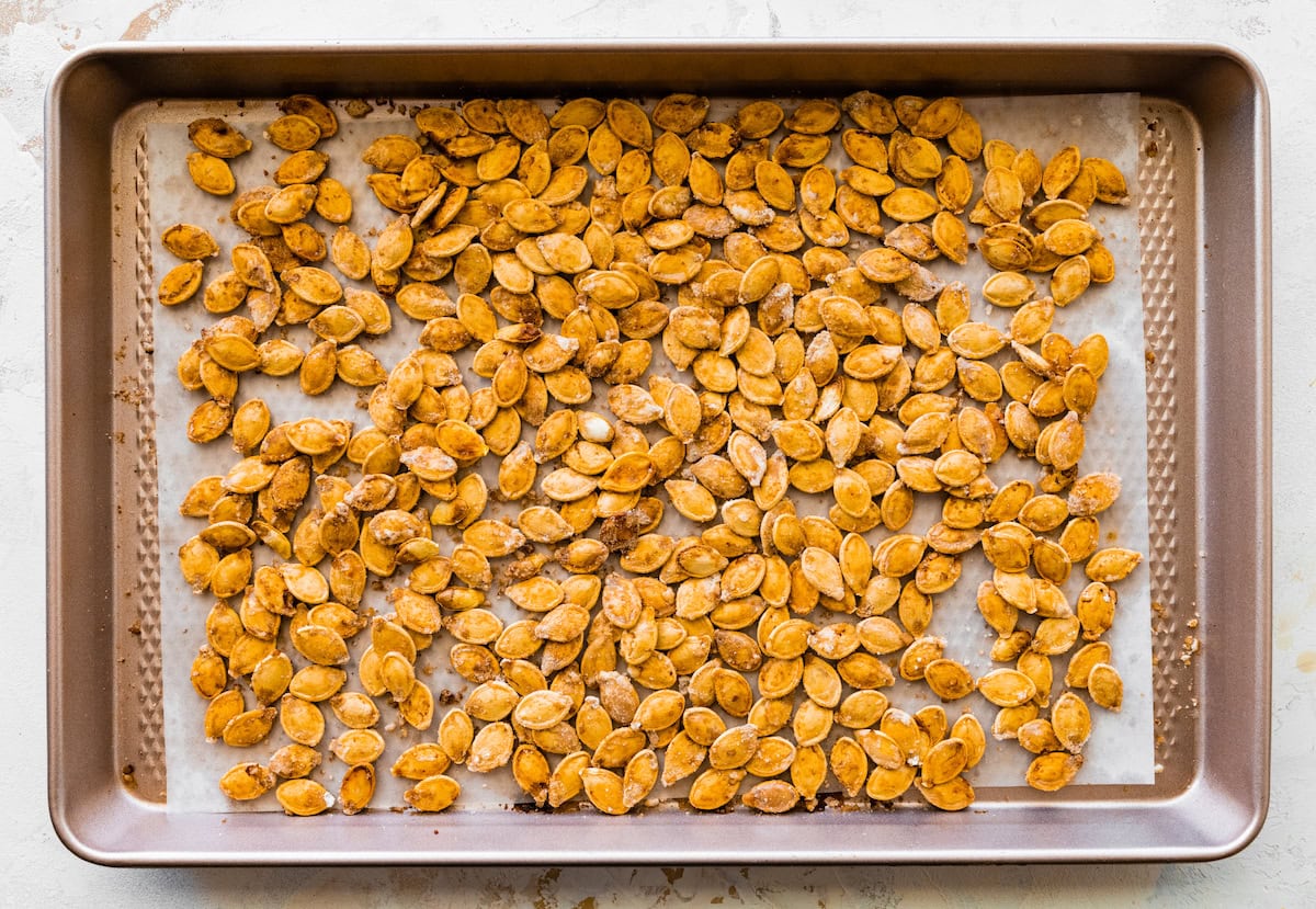 Roasted and salted pumpkin seeds on a baking tray.