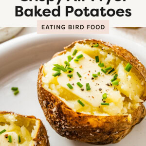 Air Fryer Baked Potato on a plate topped with butter, chives and pepper.