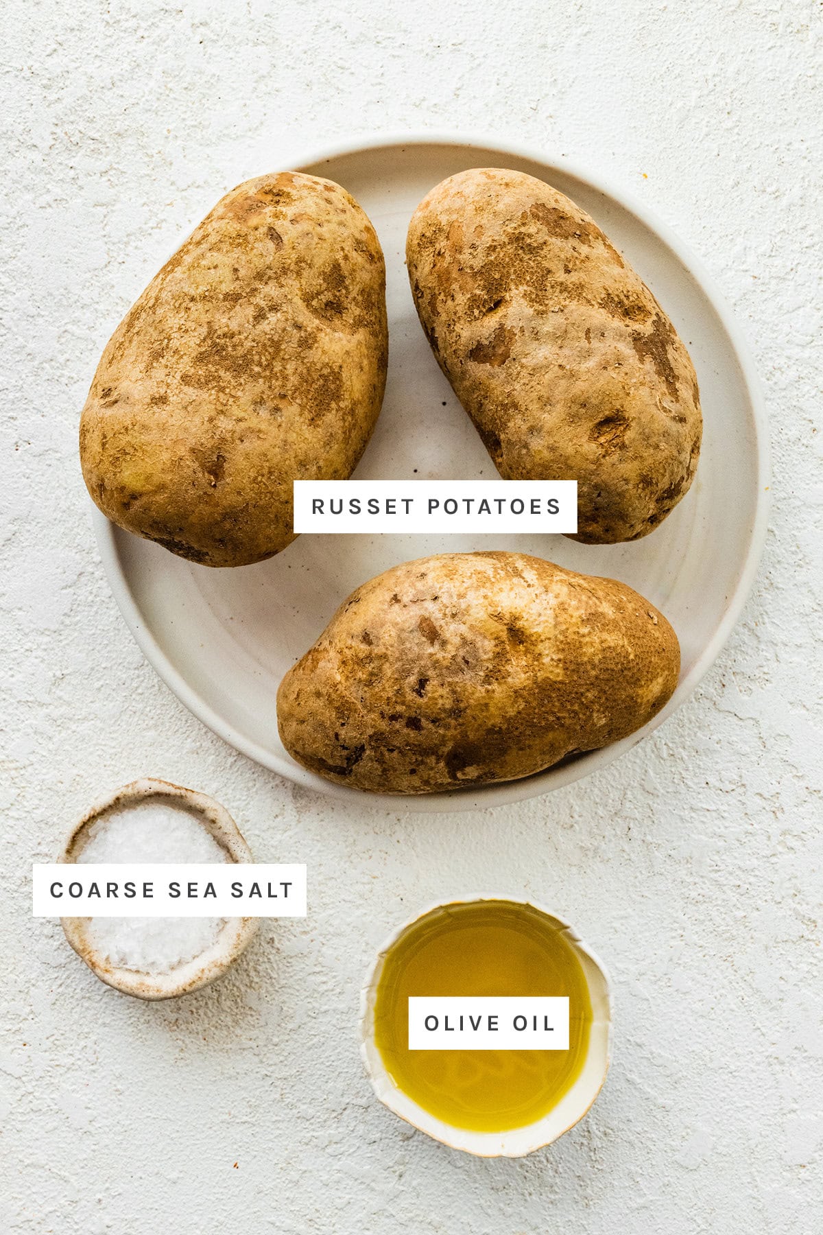 Ingredients measured out to make Air Fryer Baked Potato: russet potatoes, coarse sea salt and olive oil.