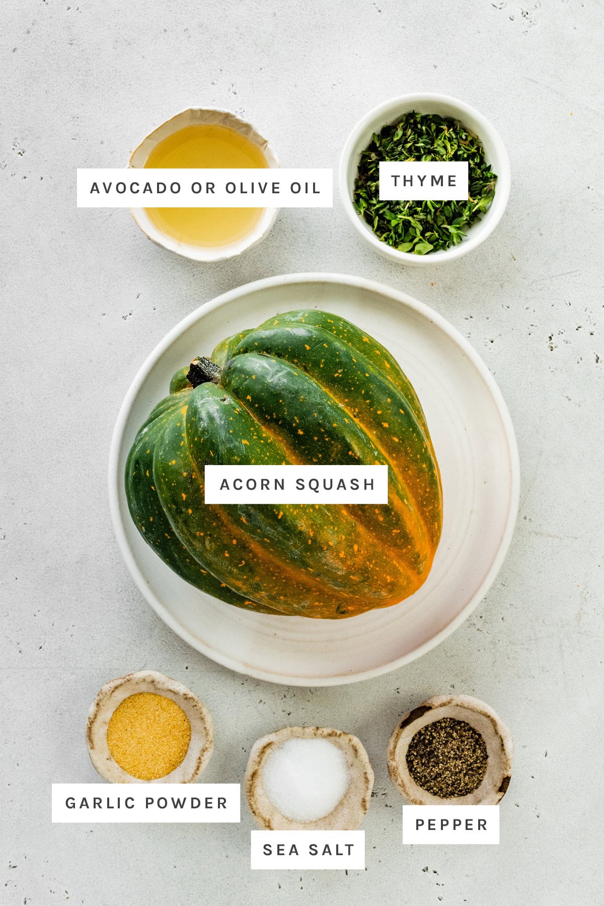 Ingredients measured out to make Roasted Acorn Squash: avocado oil, thyme, acorn squash, garlic powder, sea salt and pepper.