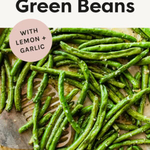 Roasted green beans on a baking sheet with a spatula.