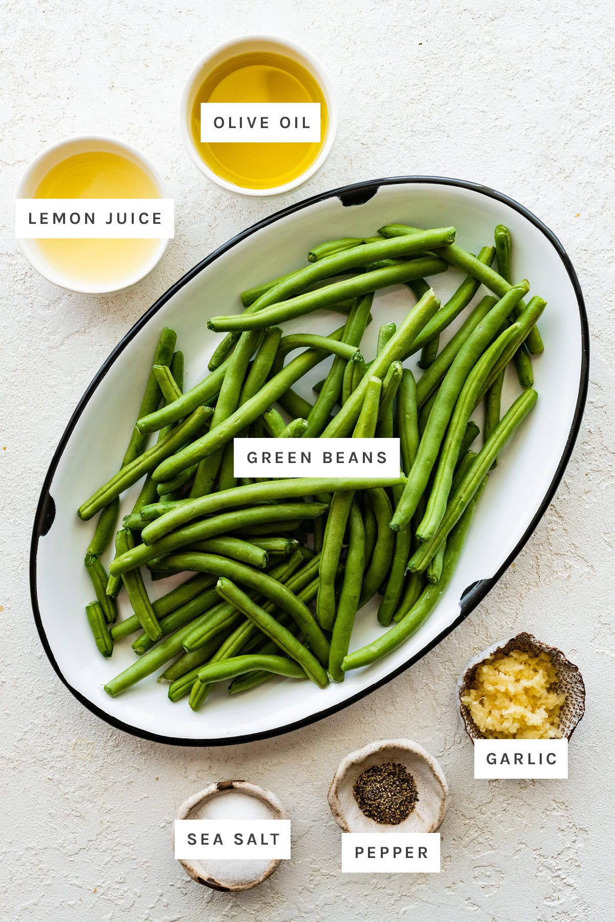 Ingredients measured out to make Roasted Green Beans: lemon juice, olive oil, green beans, sea salt, pepper and garlic.