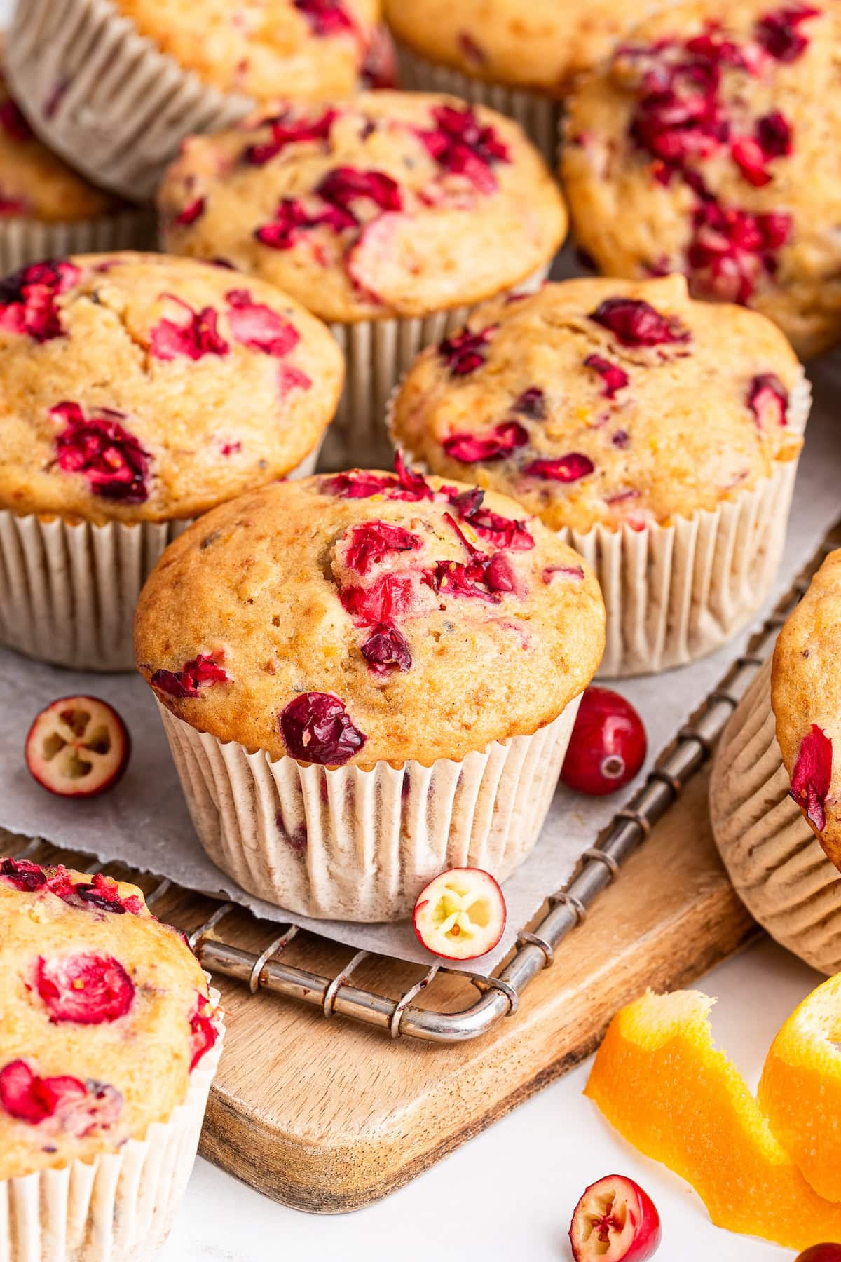 Multiple cranberry orange muffins on a cooling rack.