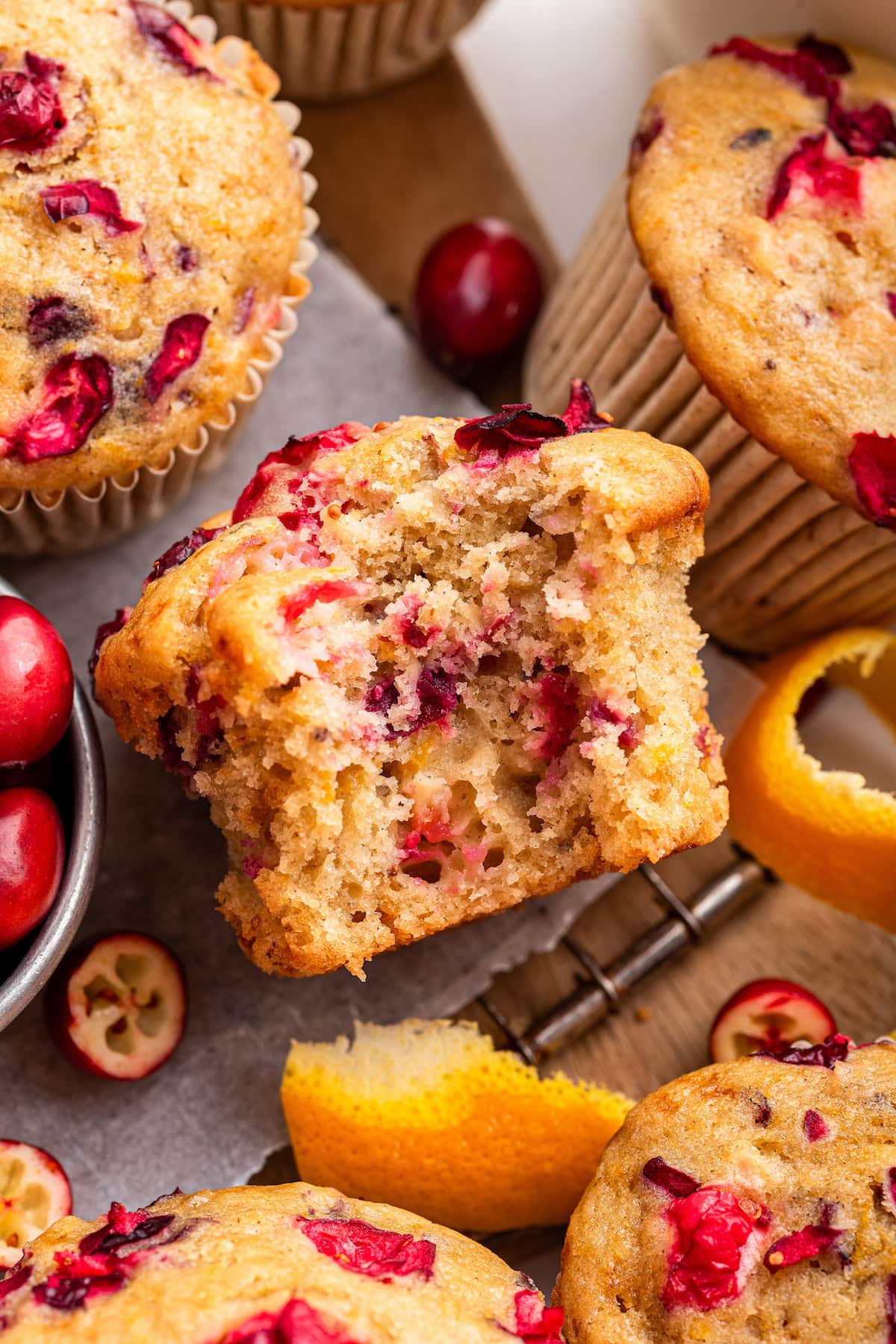Cranberry orange muffins near one another with a bite taken from one muffin.