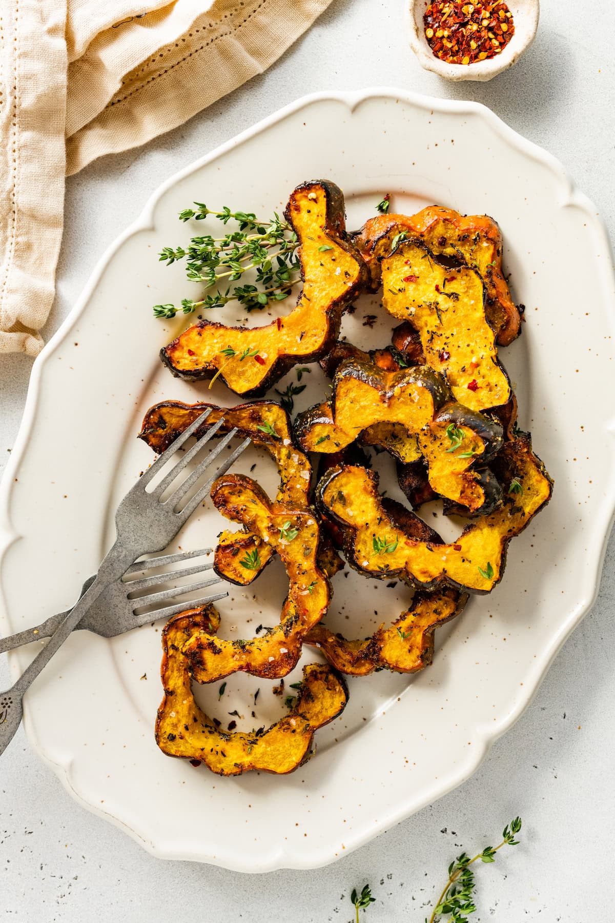 Roasted acorn squash on a white plater served with two forks.