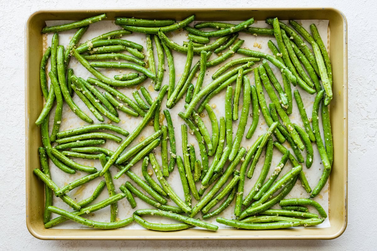 A baking tray of seasoned green beans.