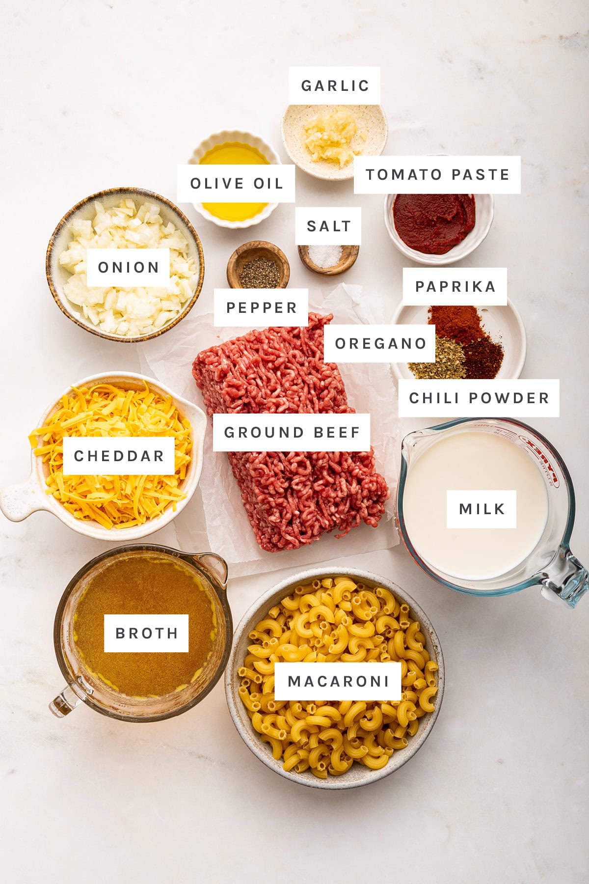 Ingredients for healthy hamburger helper include: ground beef, broth, macaroni, milk, chili powder, oregano, paprika, cheddar cheese, onion, olive oil, tomato paste, garlic, salt, and pepper.