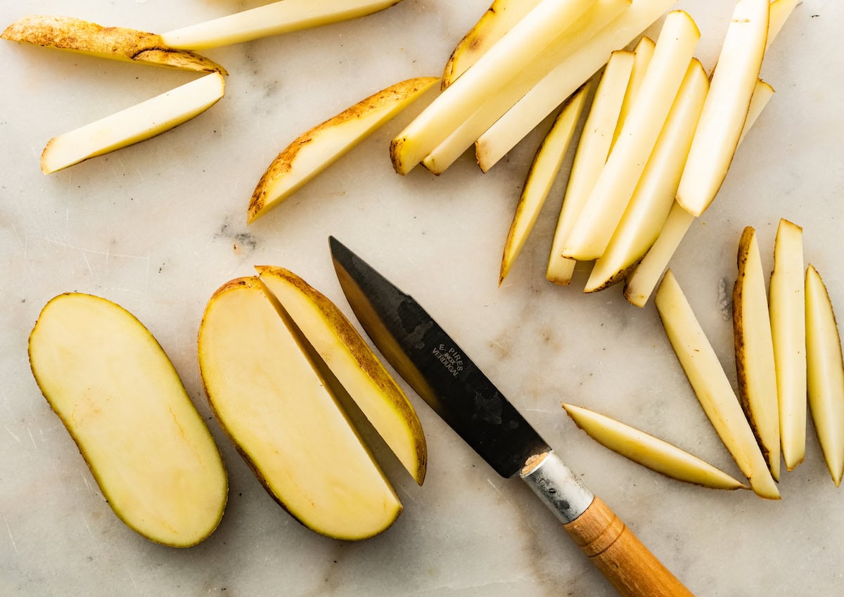 A knife is used to cut potatoes into french fries.