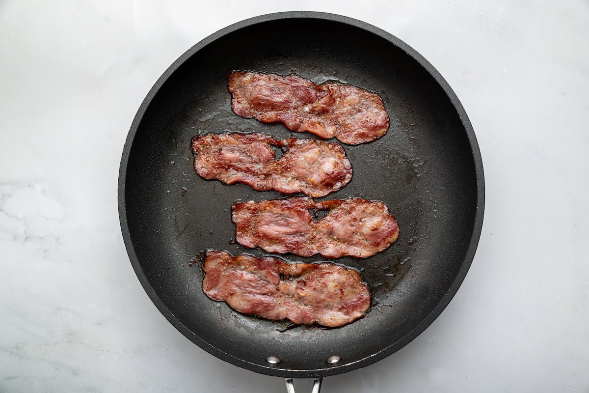 Four slices of turkey bacon cooked in a skillet.